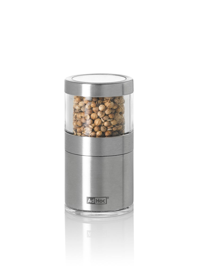 Stainless steel and glass spice grinder filled with peppercorns.