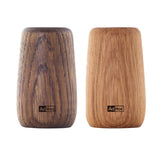Two wooden salt or pepper shakers with ’AdHoc’ branding, one darker and one lighter in color.