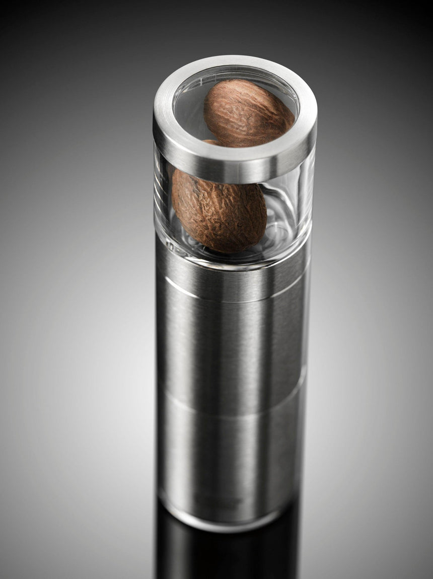 Sleek metal and glass container holding nutmeg.