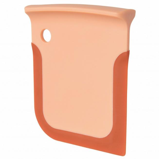Peach-colored plastic or silicone scraper with a curved edge and a hole for hanging.