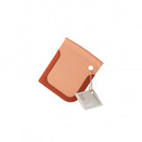Peach-colored leather wallet or cardholder with a tag attached.