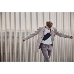 Man wearing a gray coat with outstretched arms.