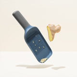 Blue plastic cheese grater with grated cheese visible.