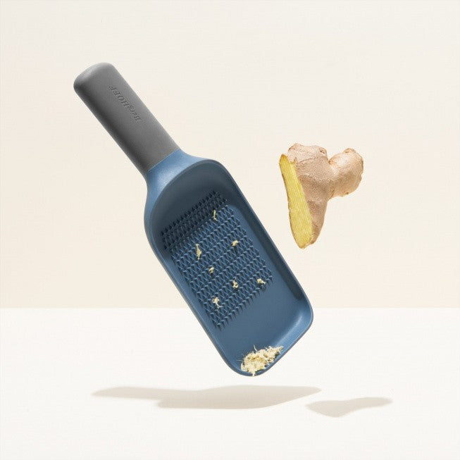 Blue plastic cheese grater with grated cheese visible.