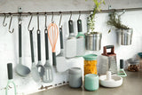 Kitchen utensils and accessories organized on a wall-mounted rack and countertop.
