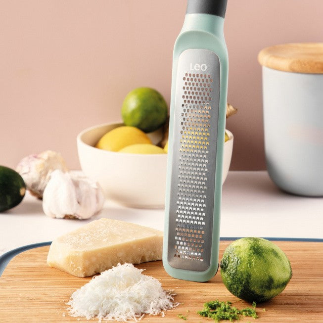 Mint-colored cheese grater with a long handle and perforated grating surface.