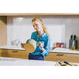 Woman in a blue shirt holding a round wooden object in a kitchen setting.